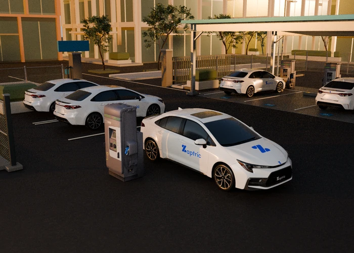Charging pedestal and branded illustrative fleet car at a solar-canopy depot